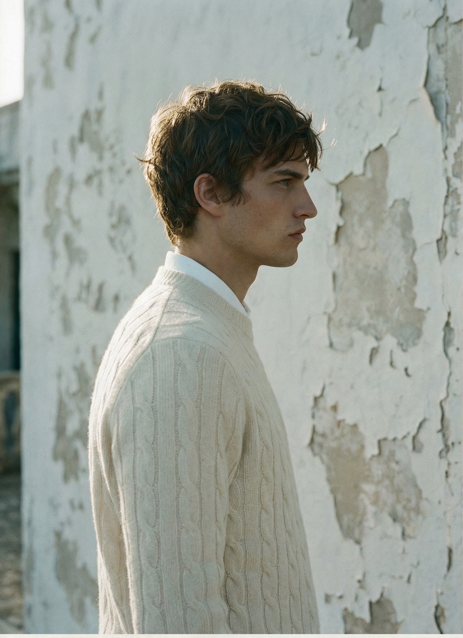 Side profile — Cable-knit sweater against stucco wall
