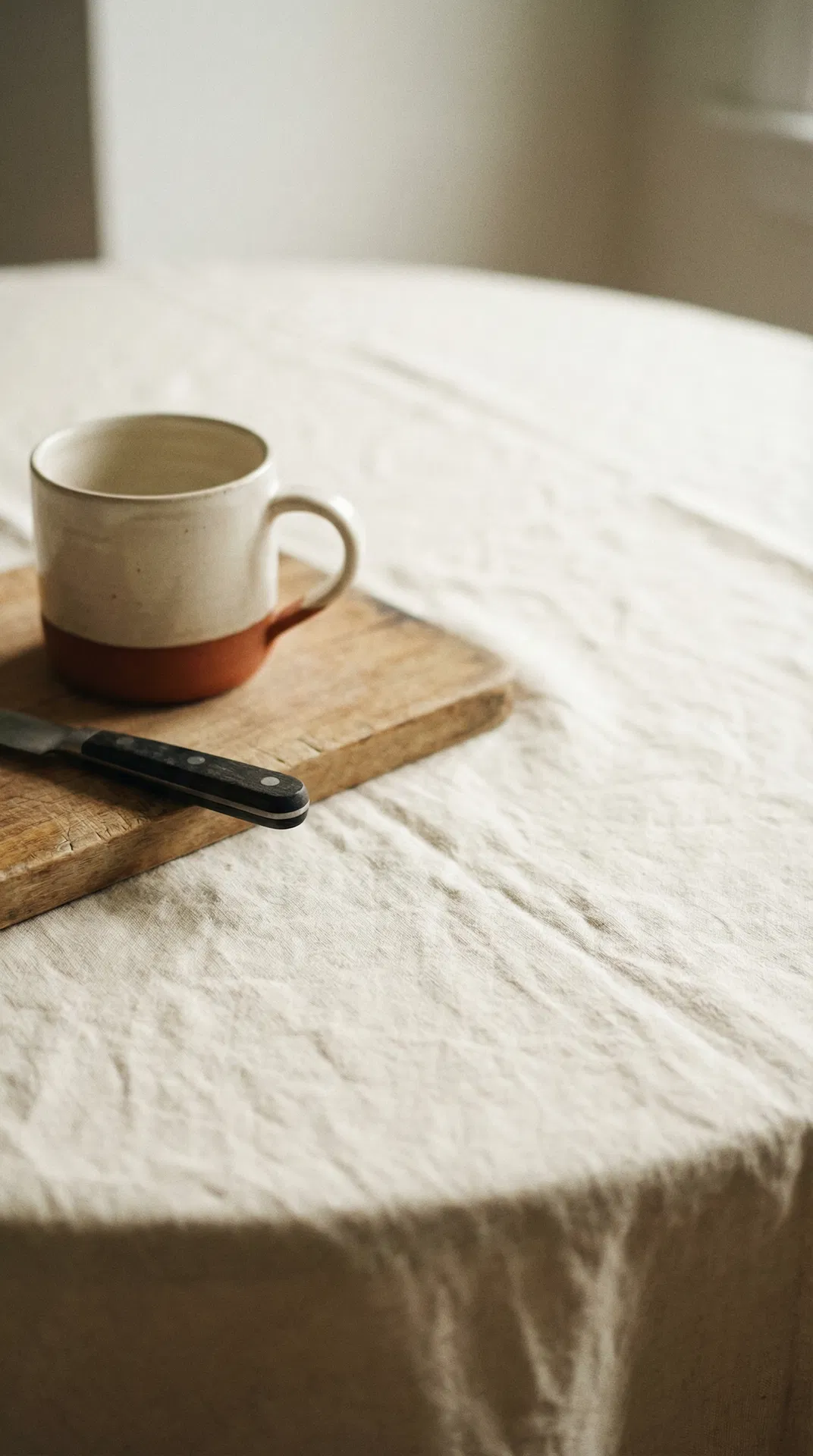 A ceramic mug and knife on linen — calm, intentional objects