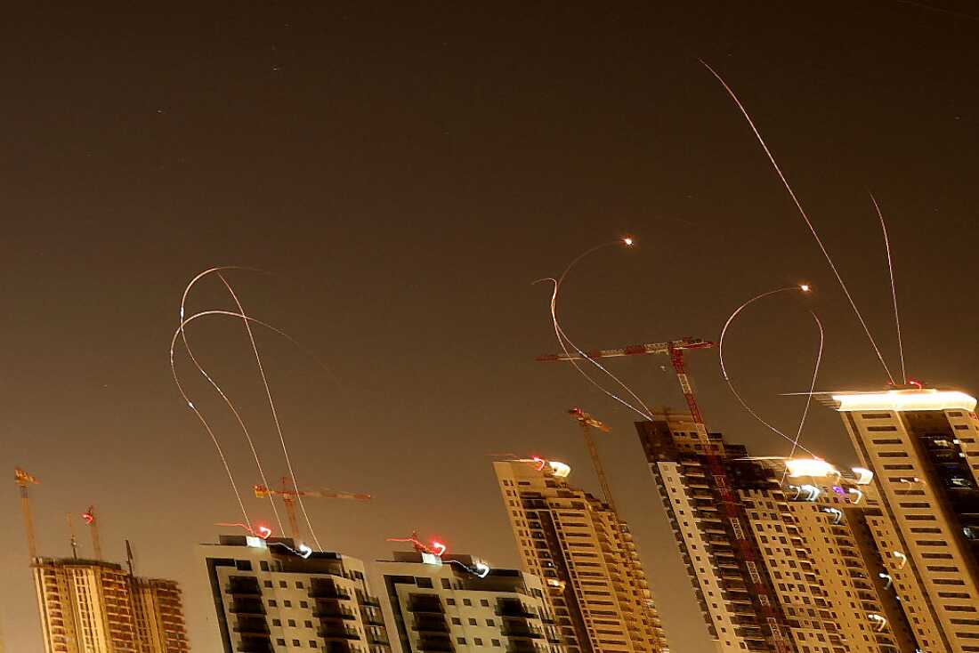 The night sky over central Israel illuminated by missile intercepts over a city skyline