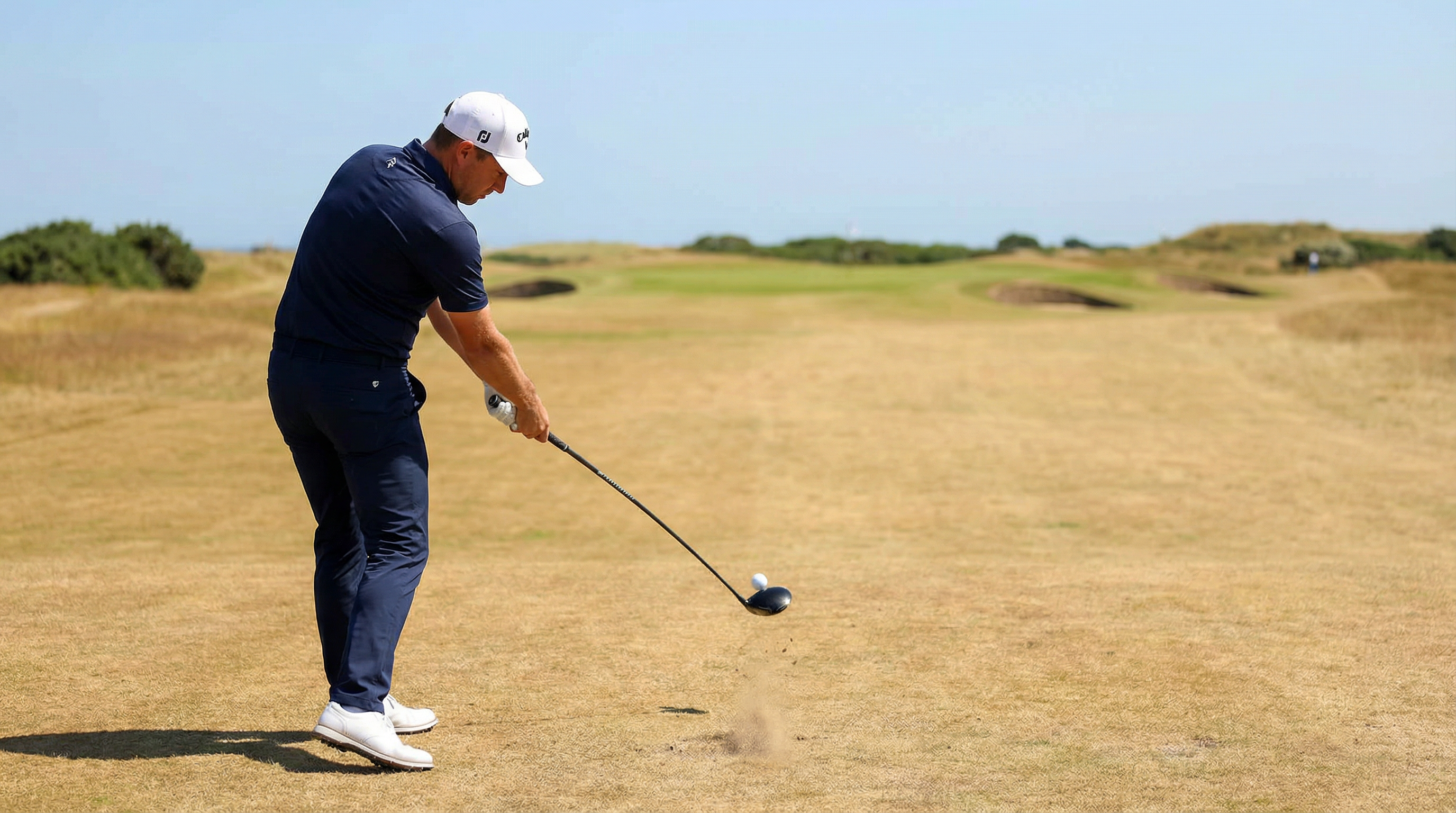 Golfer hitting a controlled tee shot on a fast firm course