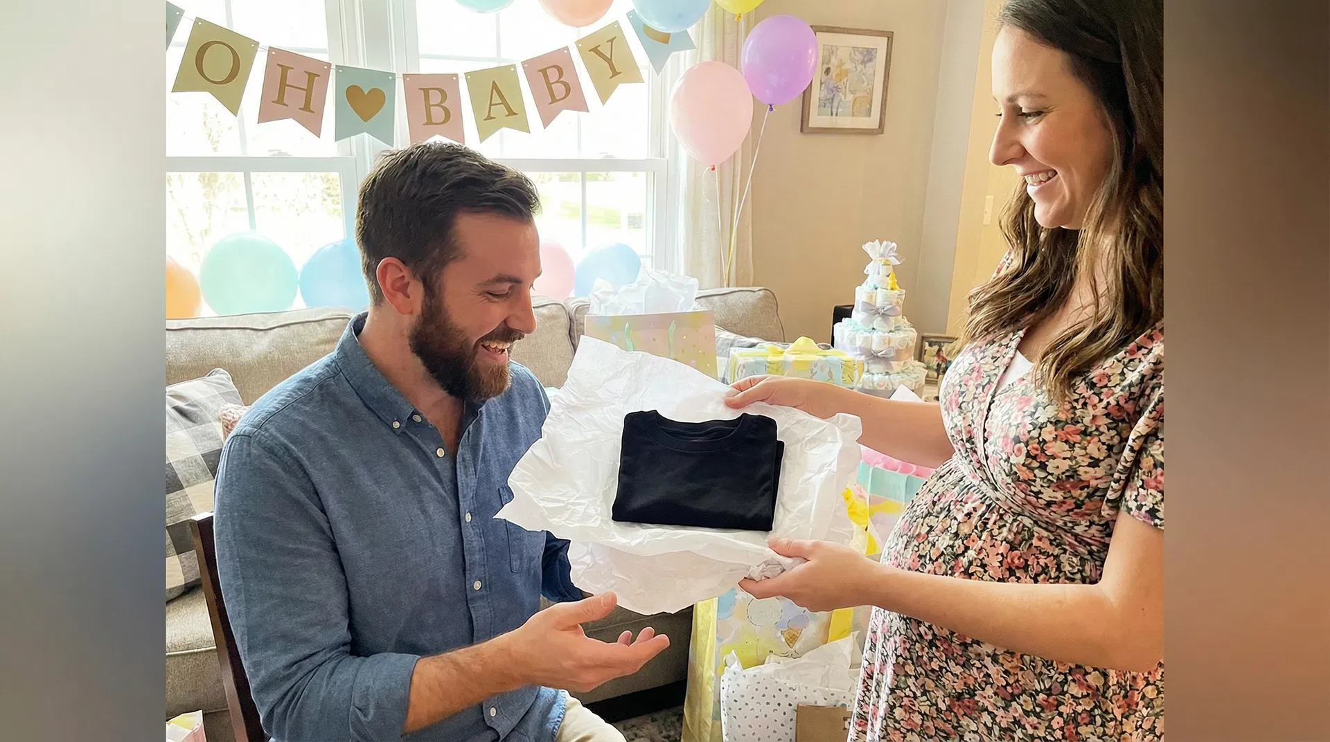 Expecting father receiving a Lior Kangaroo T-Shirt as a gift at a baby shower, grinning with surprise