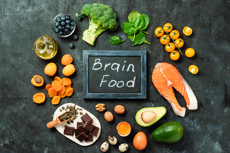 Image of various brain-boosting foods like berries, nuts, leafy greens, and fish, arranged aesthetically.