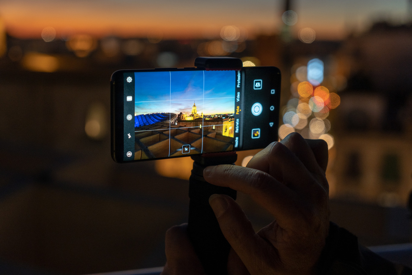 Pessoa usando o celular para tirar foto em ambiente noturno com luzes de Natal