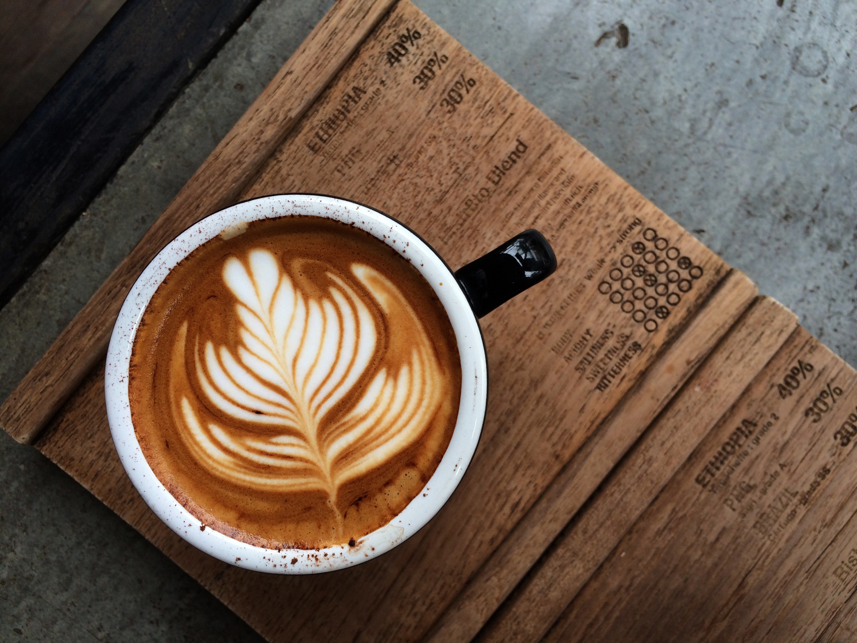 A steaming cup of coffee with latte art, surrounded by coffee beans.