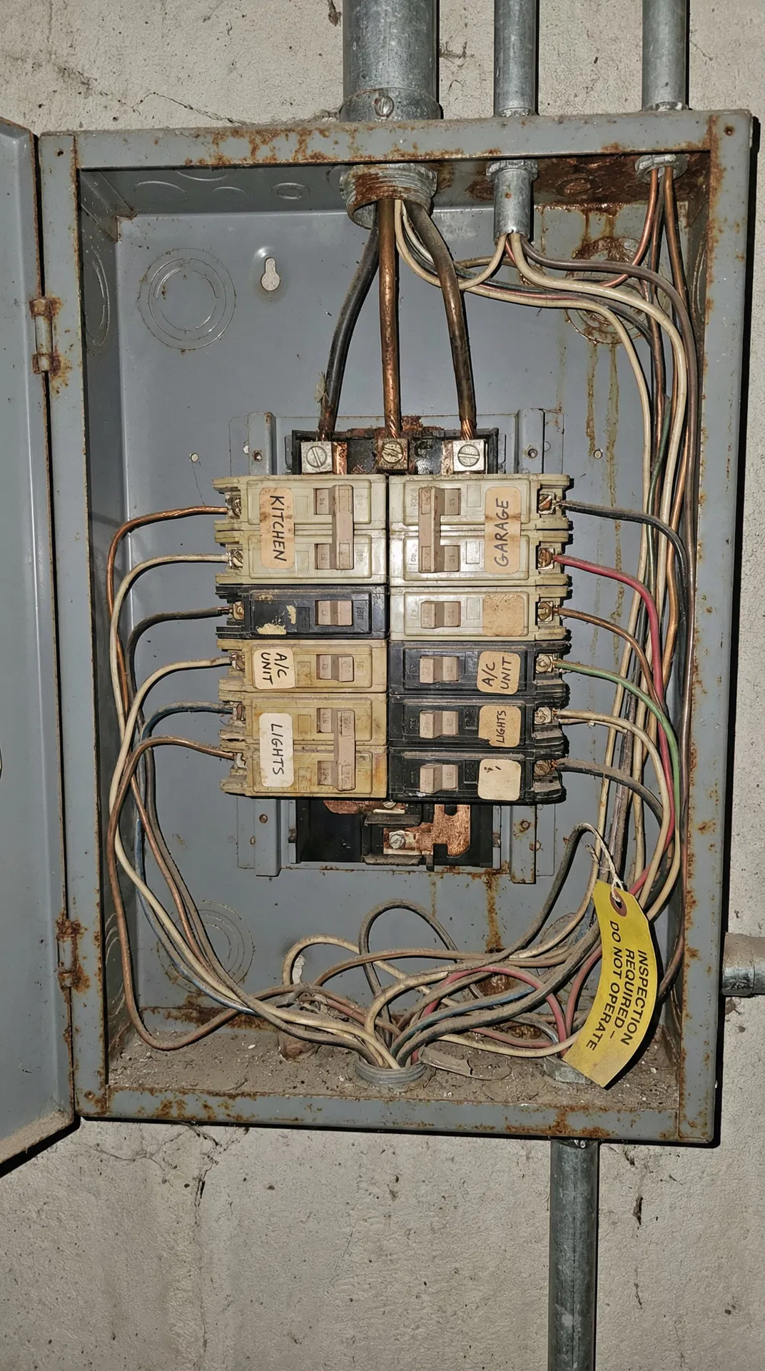 Outdated electrical panel from 1970s showing aged breakers and rust