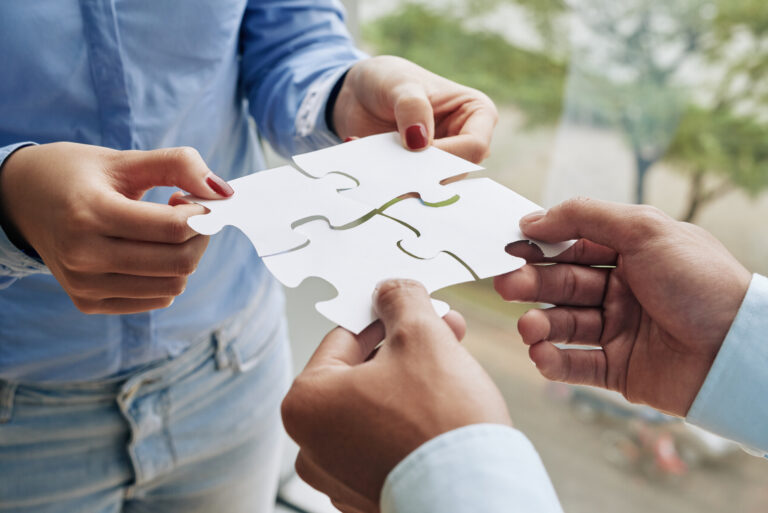 Pessoas montando um quebra-cabeça, simbolizando a cooperação e a economia solidária.