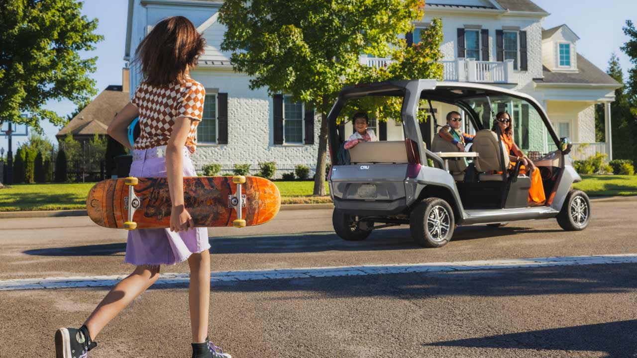A family driving a golf cart in a residential neighborhood.