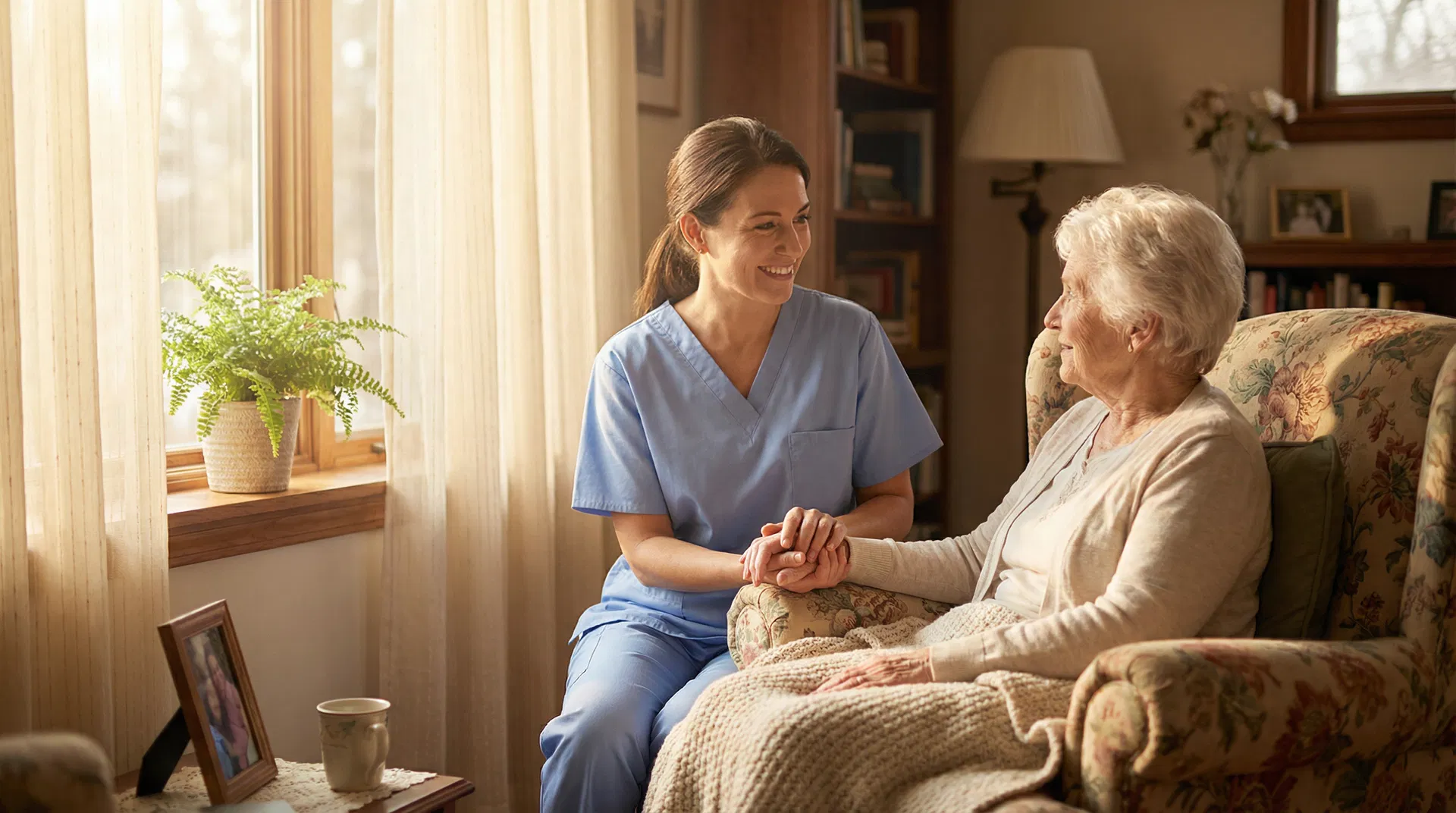 A compassionate Optimal Home Care caregiver sitting with an elderly client in a warm, sunlit home