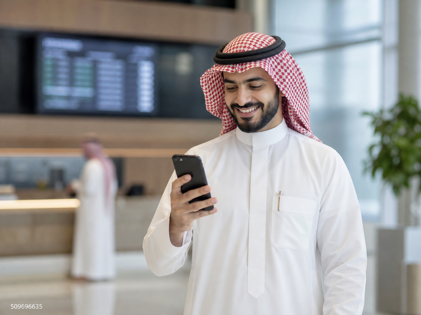 صورة لرجل سعودي سعيد يستخدم هاتفه بعد تحويل راتبه