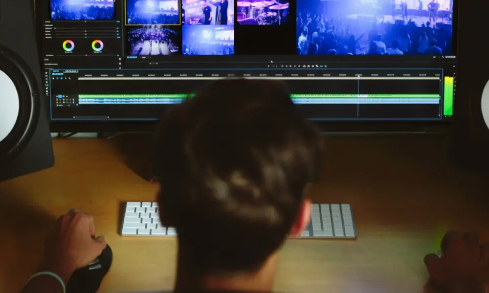 Jovem operando mesa de edição de vídeo em ambiente de produção audiovisual.
