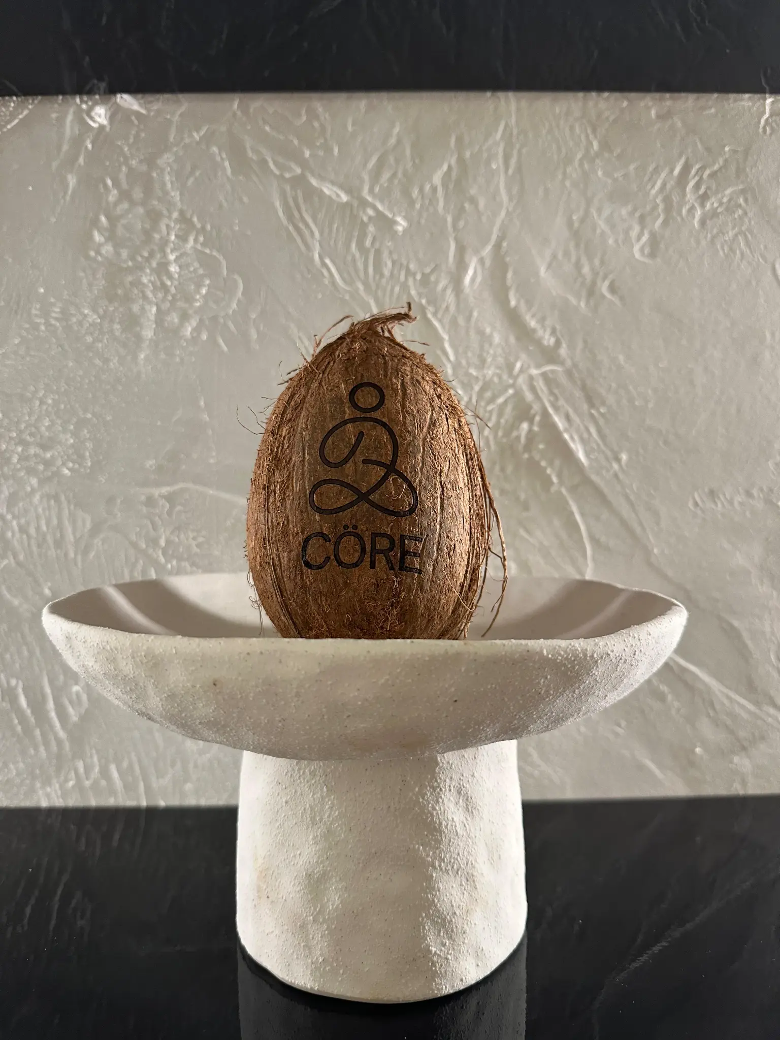 CÖRE branded coconut on ceramic pedestal