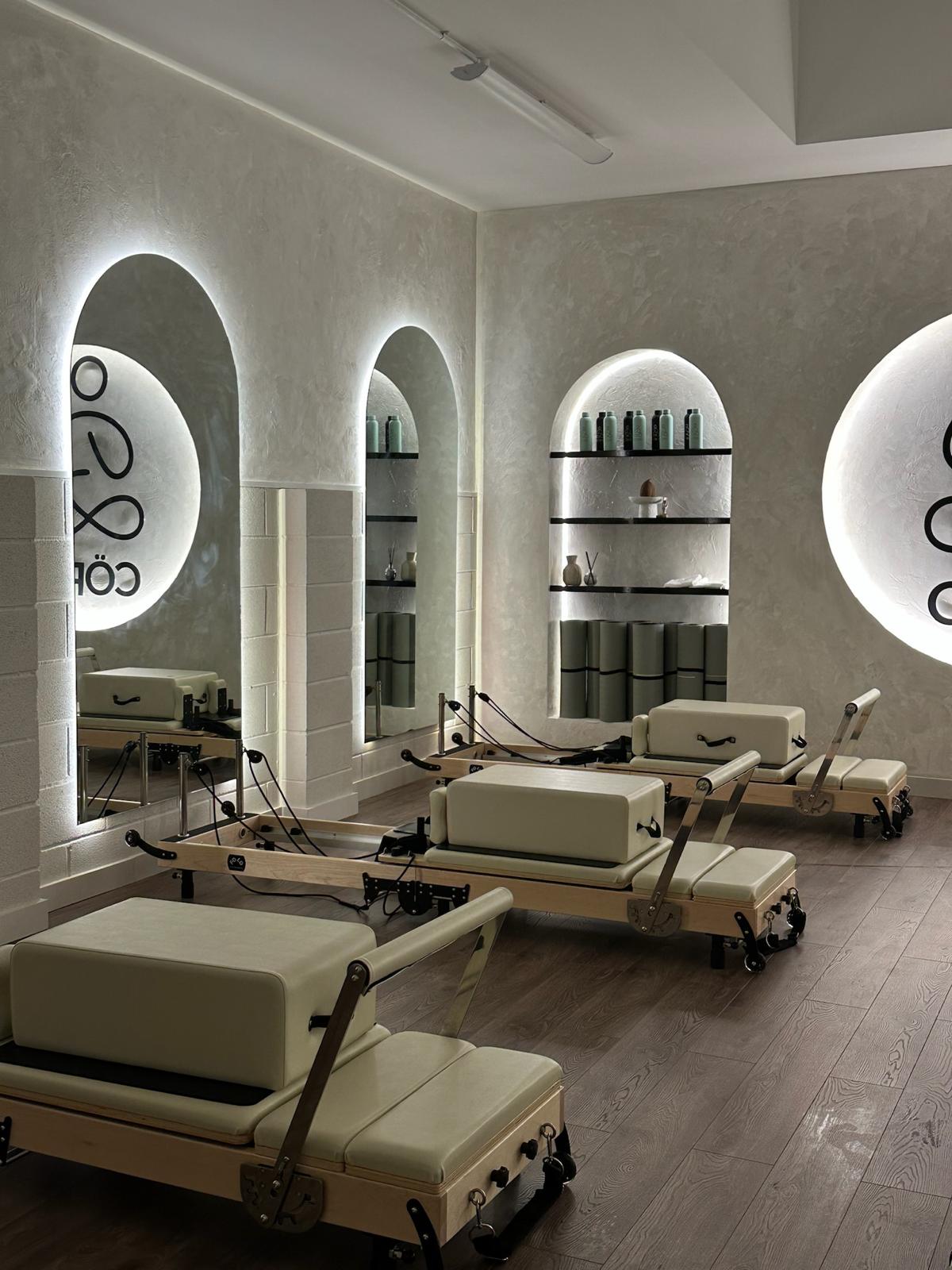 Cöre Studio reformer room with arched alcoves and illuminated logo