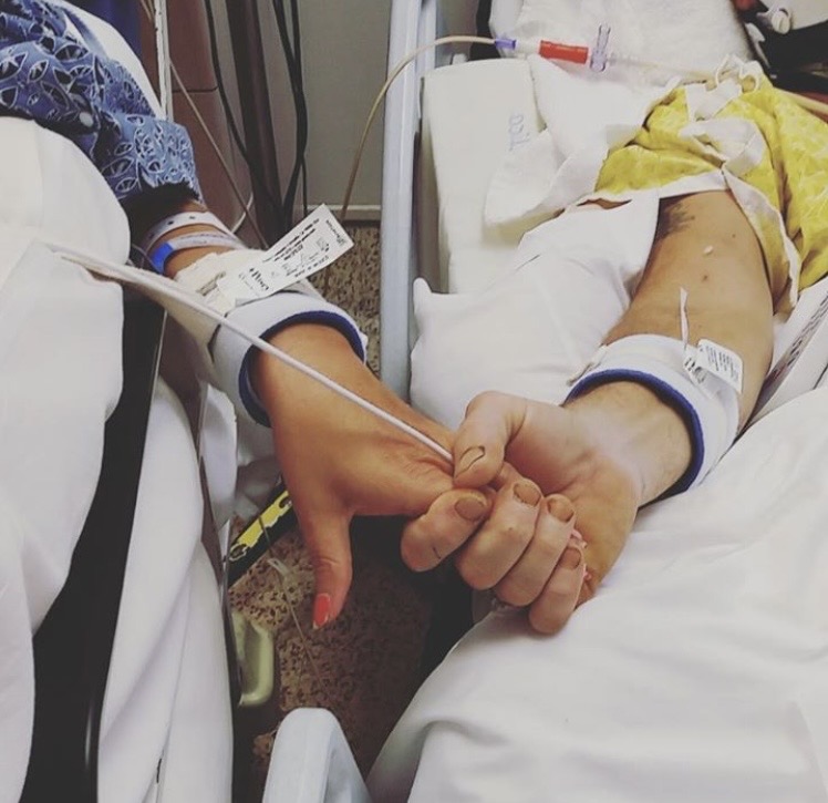 Mark and Rachelle Benishek holding hands in the hospital