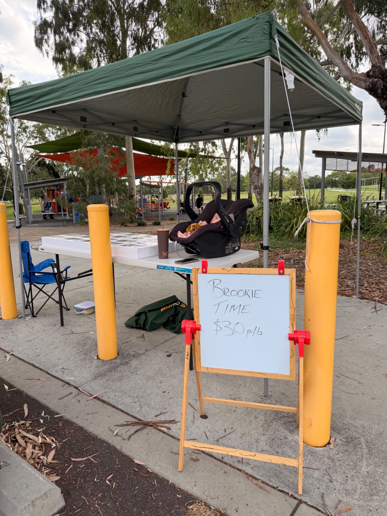 The first Brookie Time pop-up in Redbank โ the gazebo, the handwritten sign, and one of the kids in a car seat on the table