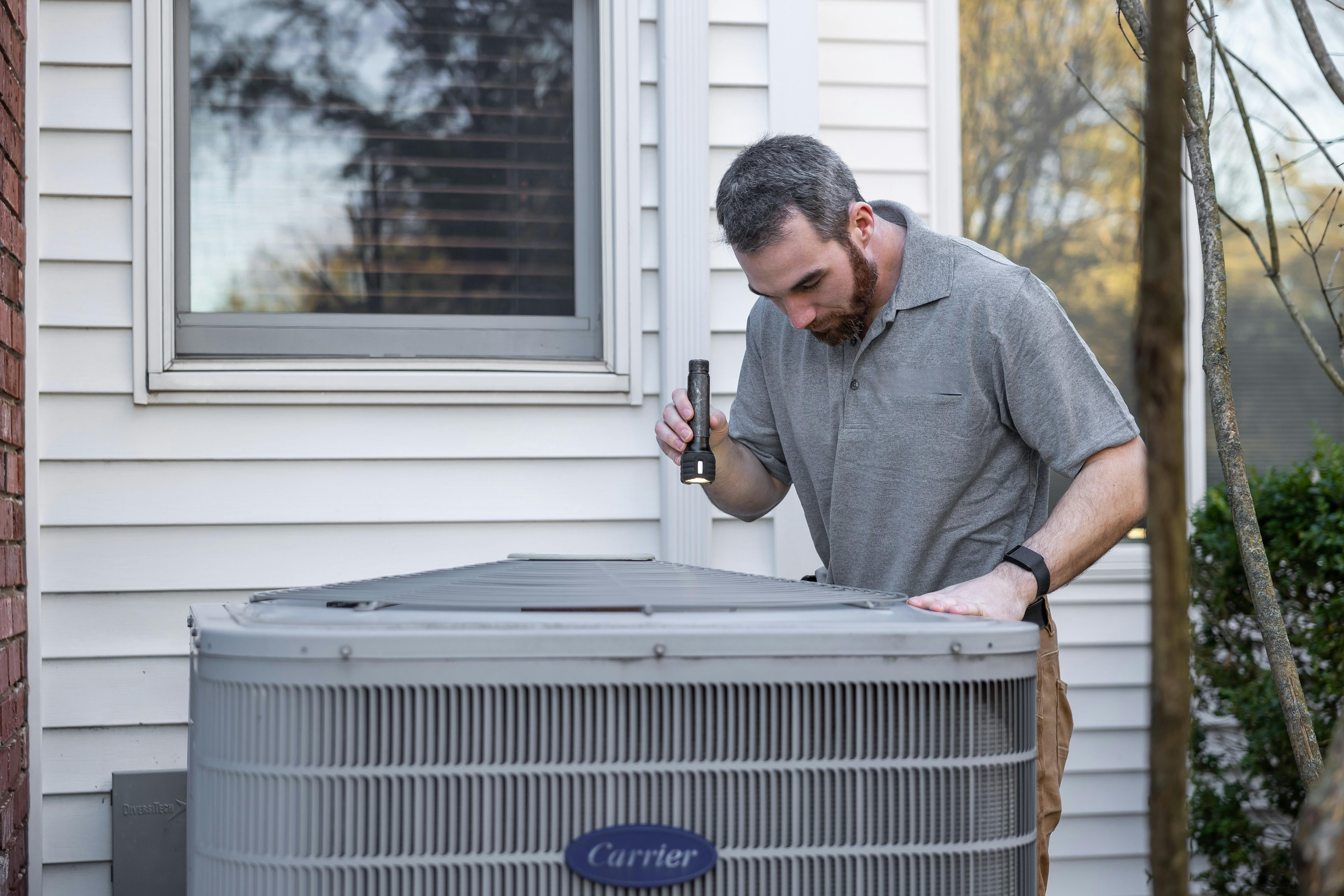 SOS Home Solutions HVAC technician inspecting air conditioning unit