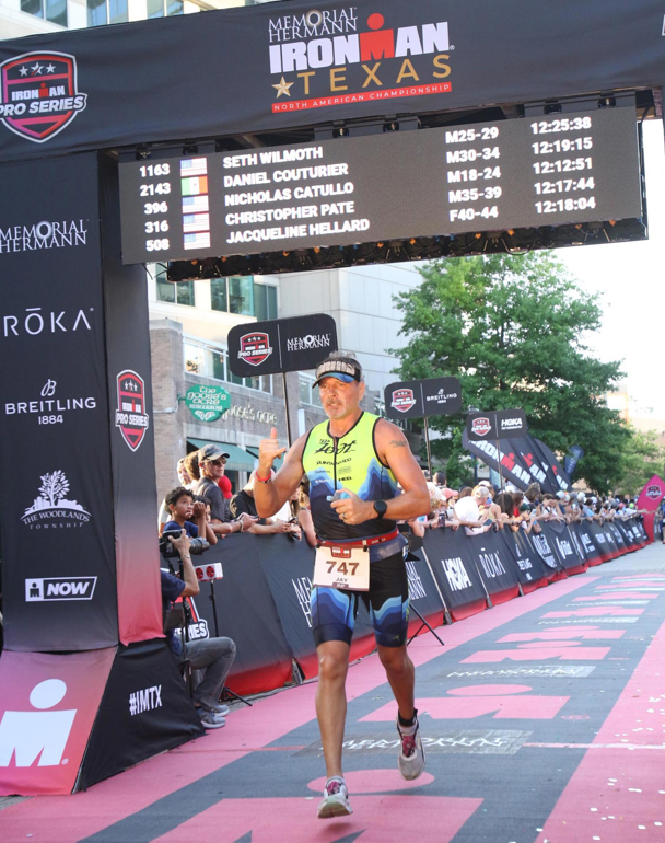 Jay crossing the Ironman Texas finish line arch — bib #747